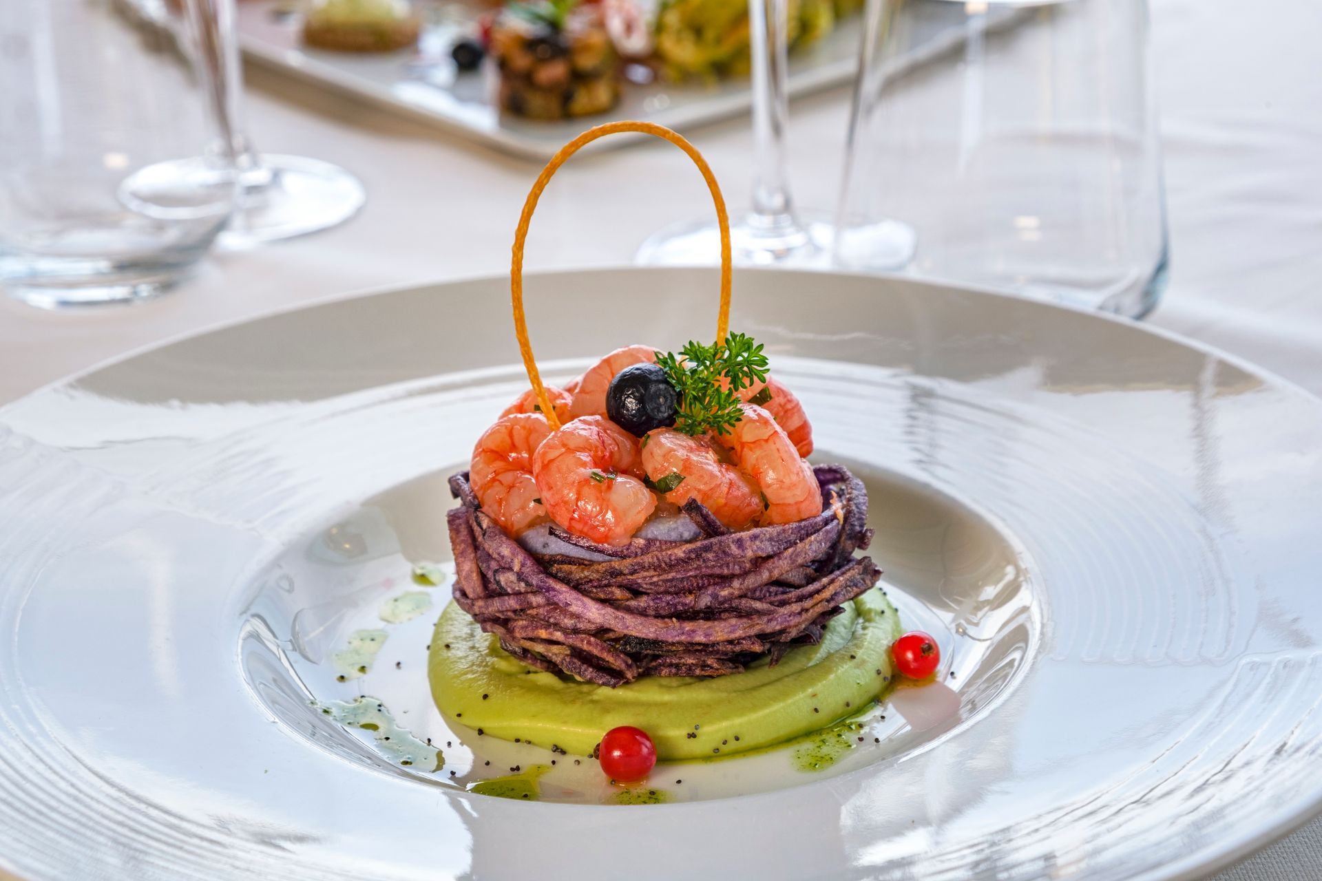 Tartare di tonno gourmet con avocado, guarnita su un piatto bianco a un tavolo da pranzo raffinato.