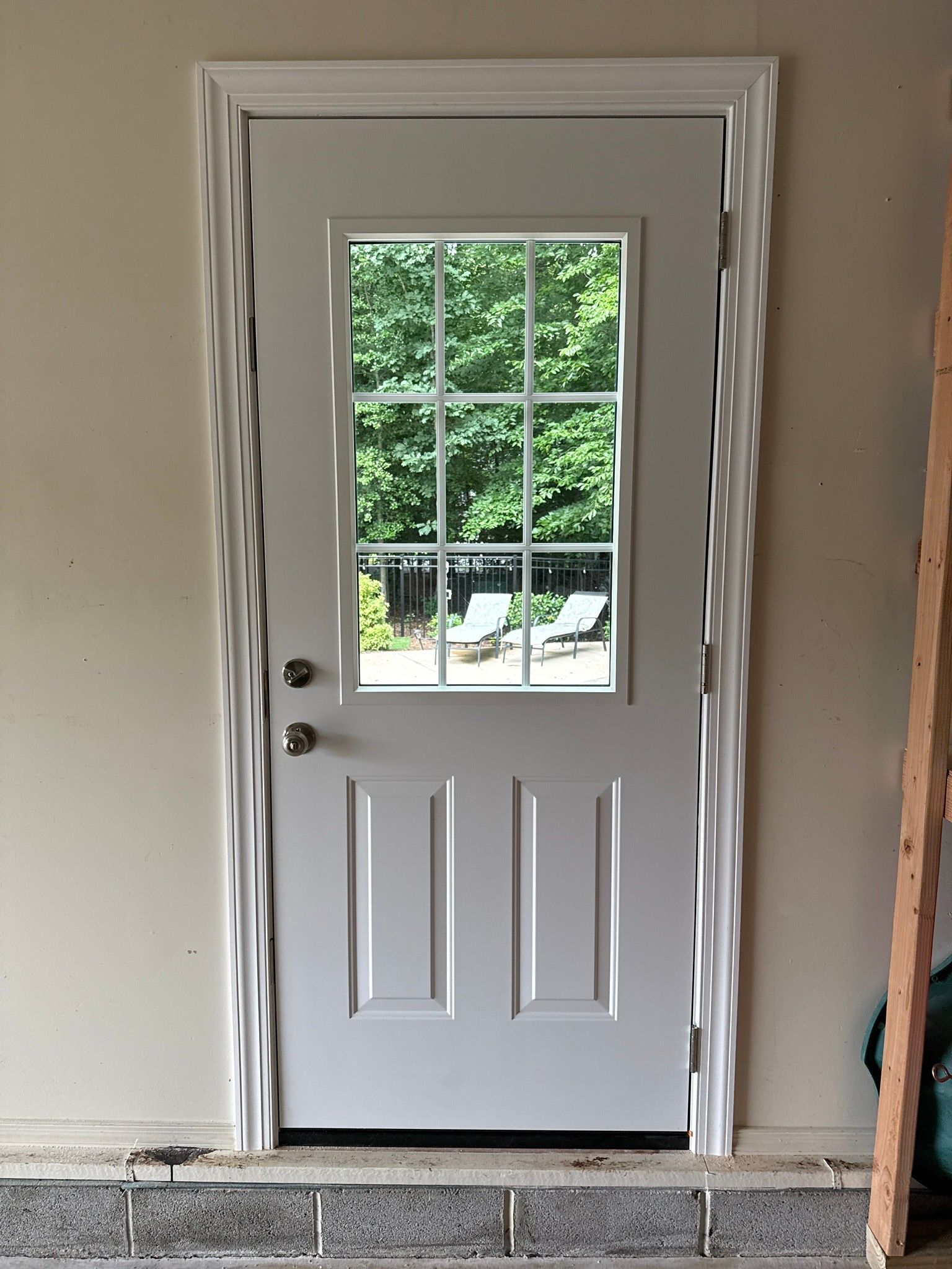 White front door with window panes, installed in a doorway under construction.