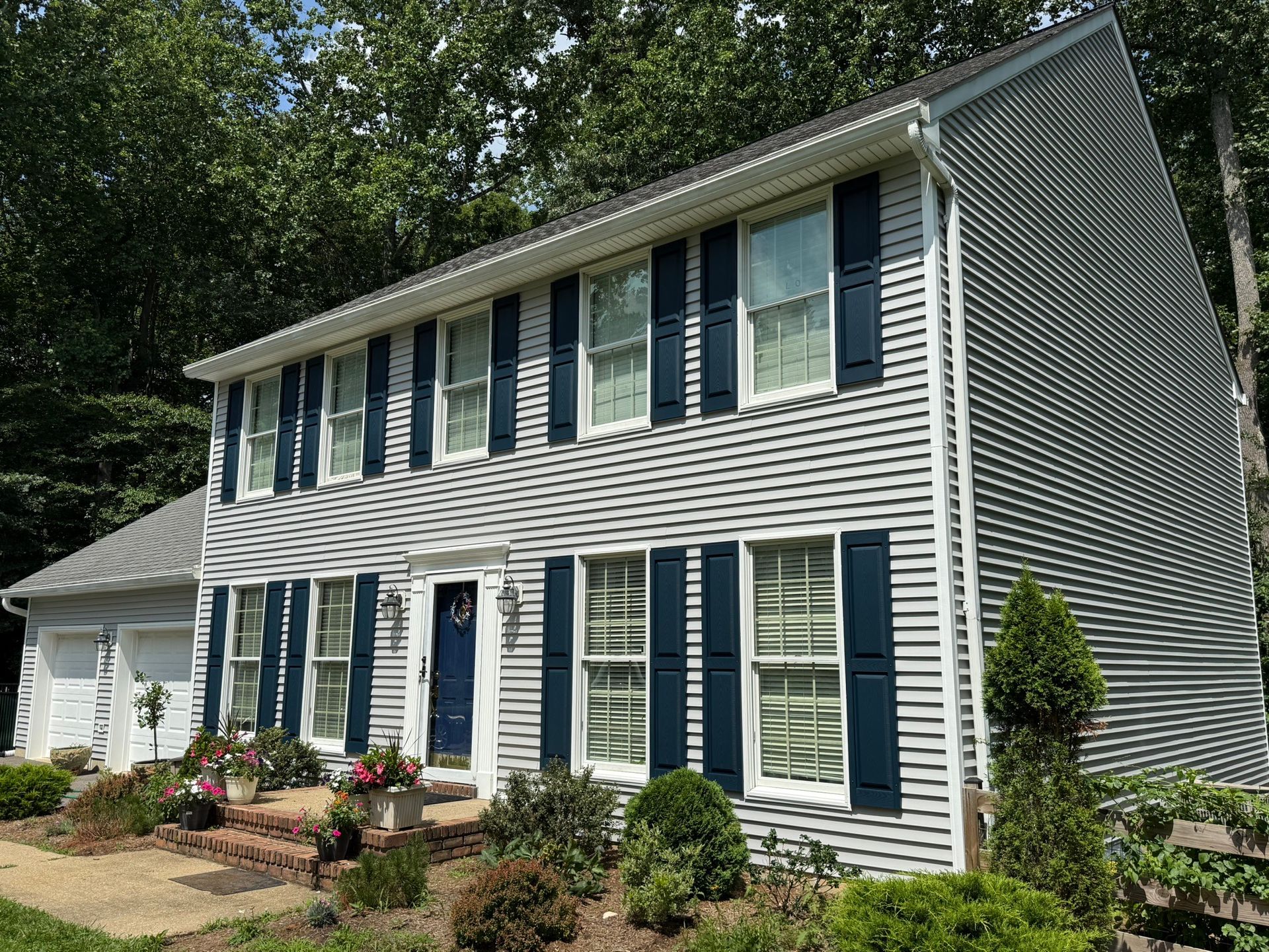White two-story house with blue shutters and a landscaped front yard