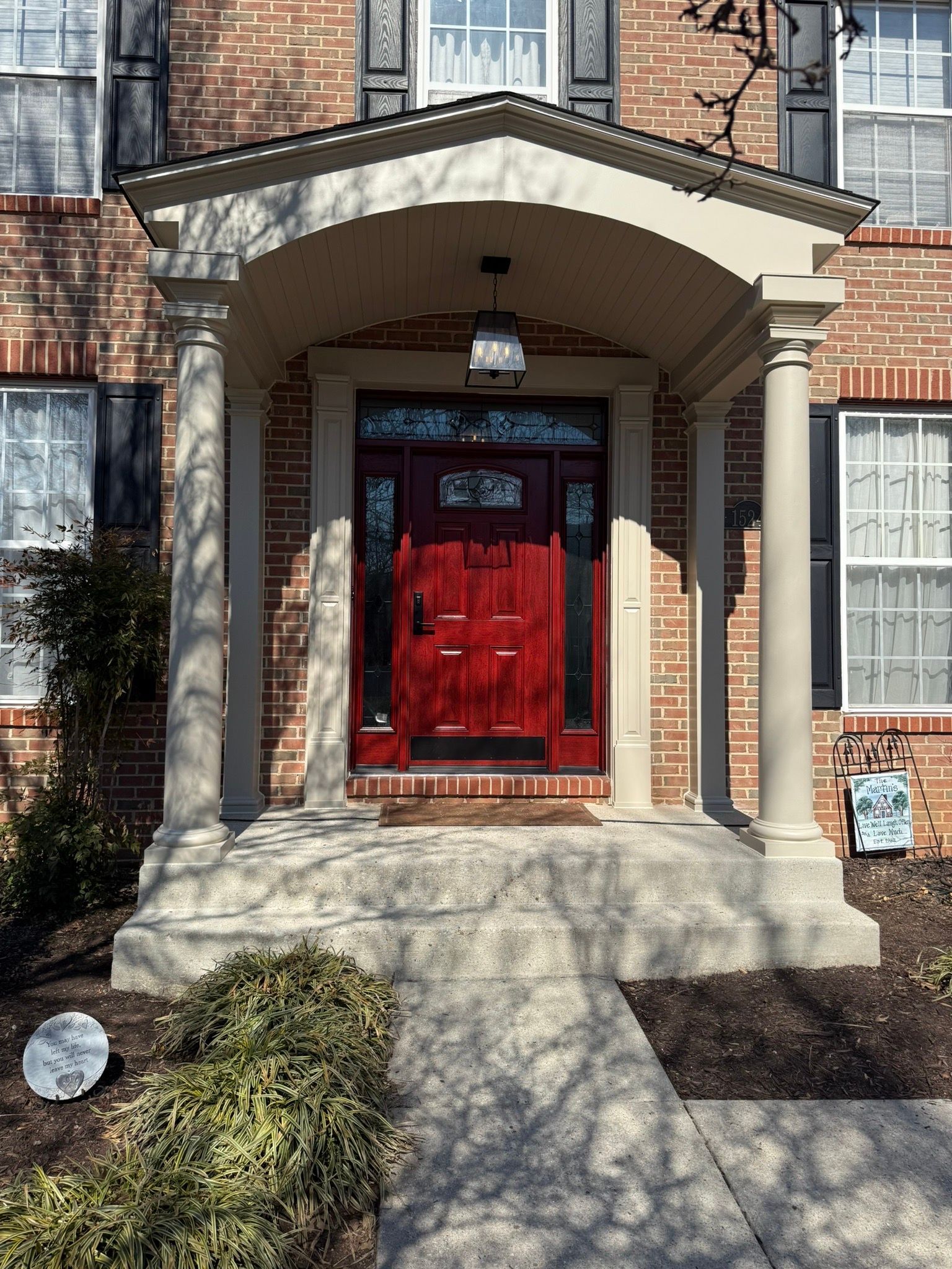 Brick townhouse entrance with red double doors, stone columns, and a small front stoop.