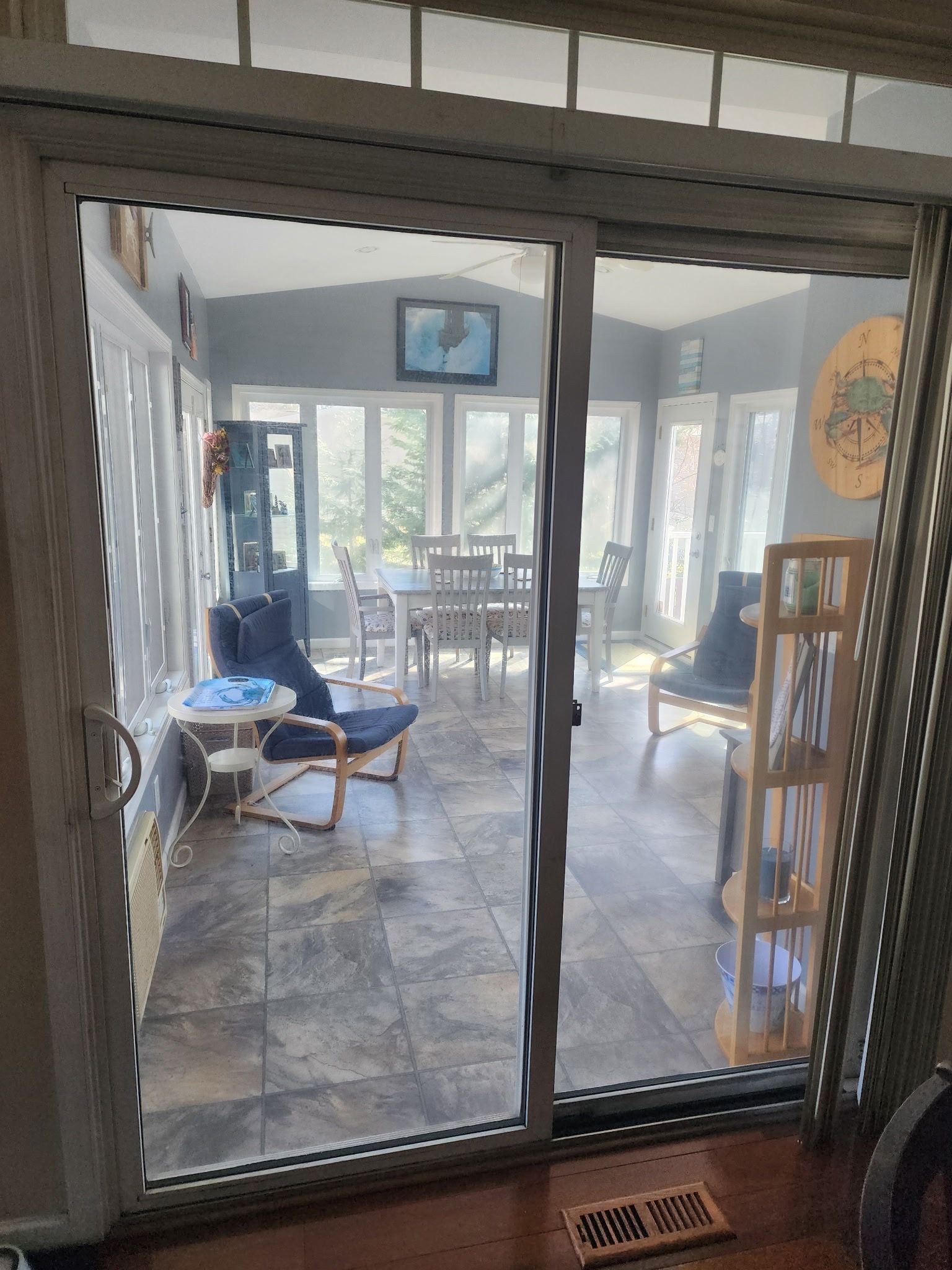 Sliding glass doors open to a bright patio room with tiled floor, chairs, and a table near windows.