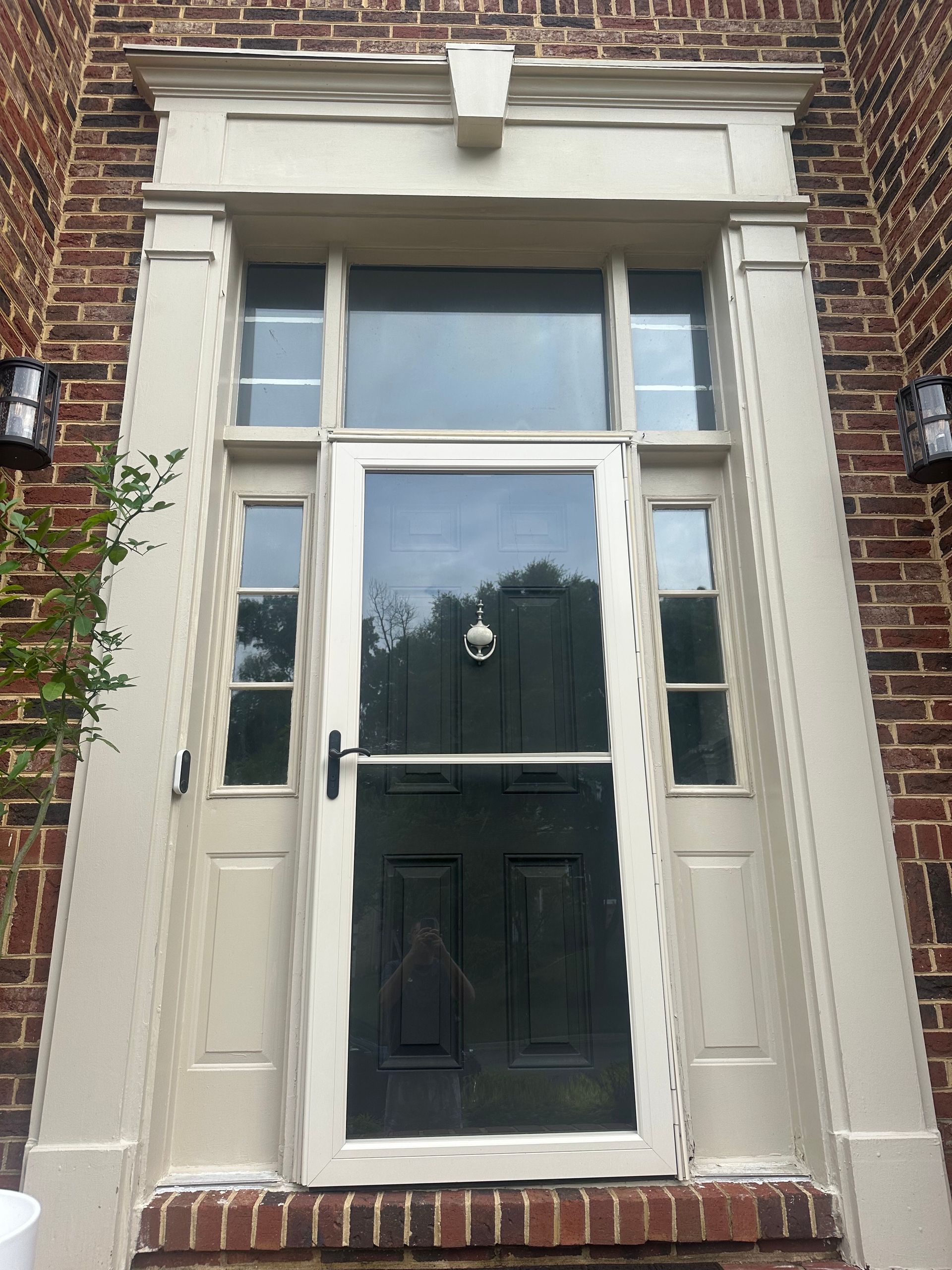 Front door of a brick house with white trim and a black lower panel.