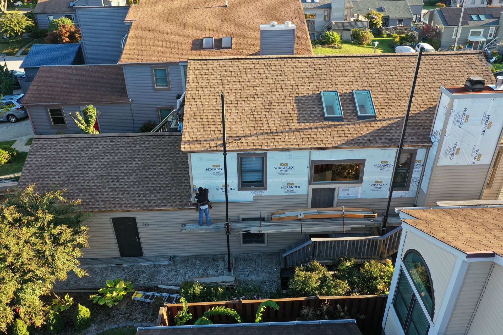 Aerial view of a narrow street between houses with tiled roofs, solar panels, and a person walking below.