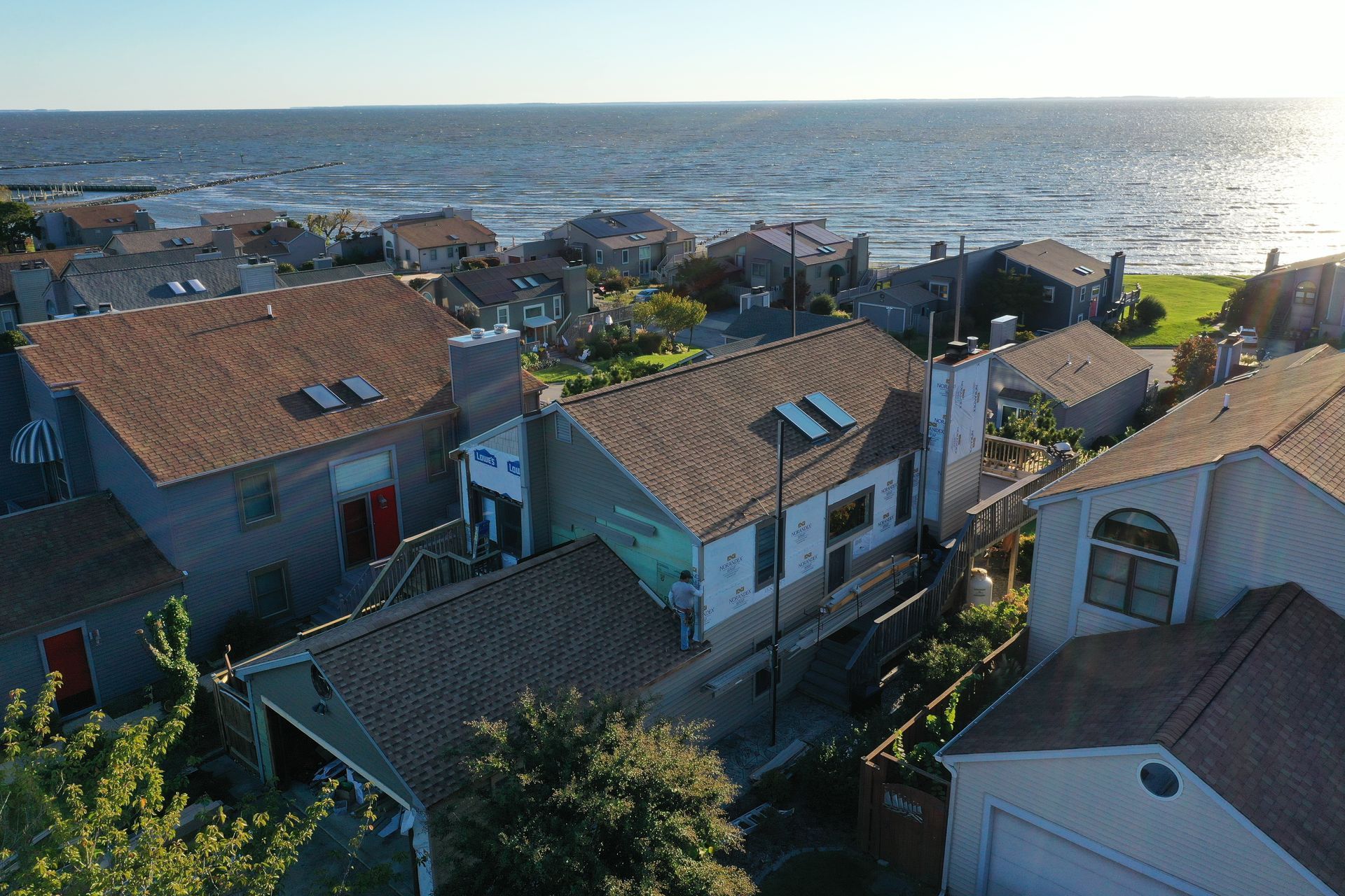 Coastal village rooftops beside the sea at sunset, with bright water in the background