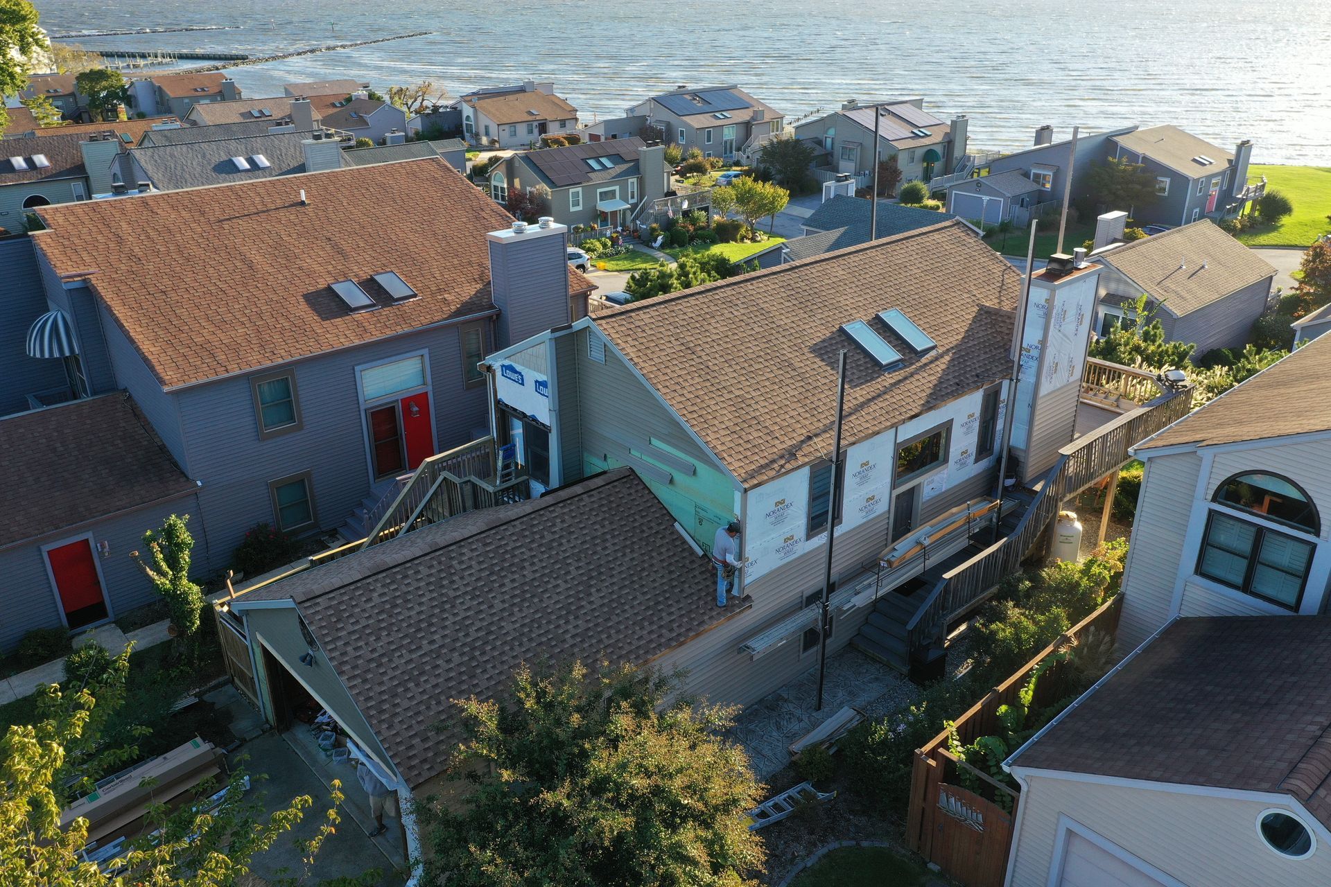Coastal village houses with red-tiled roofs overlooking the sea at sunset.