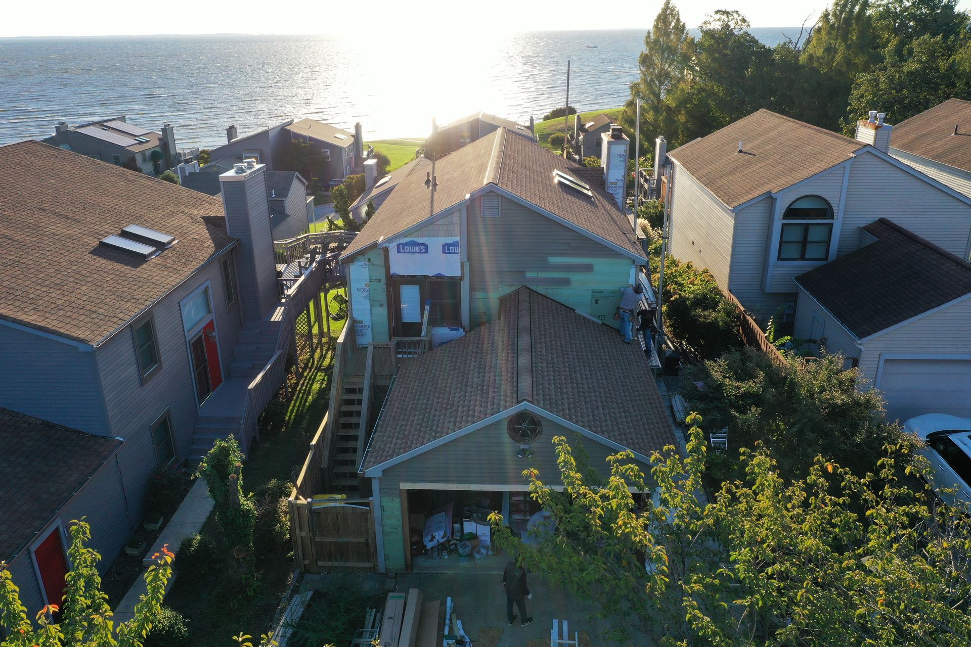 Sunlit coastal houses with tiled roofs overlooking the ocean at sunset