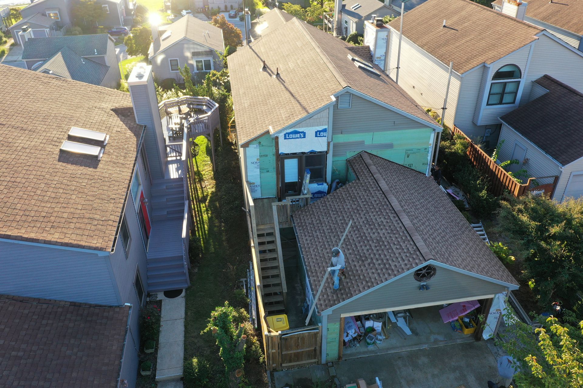 Aerial view of a narrow residential alley between houses with tan and teal roofs.