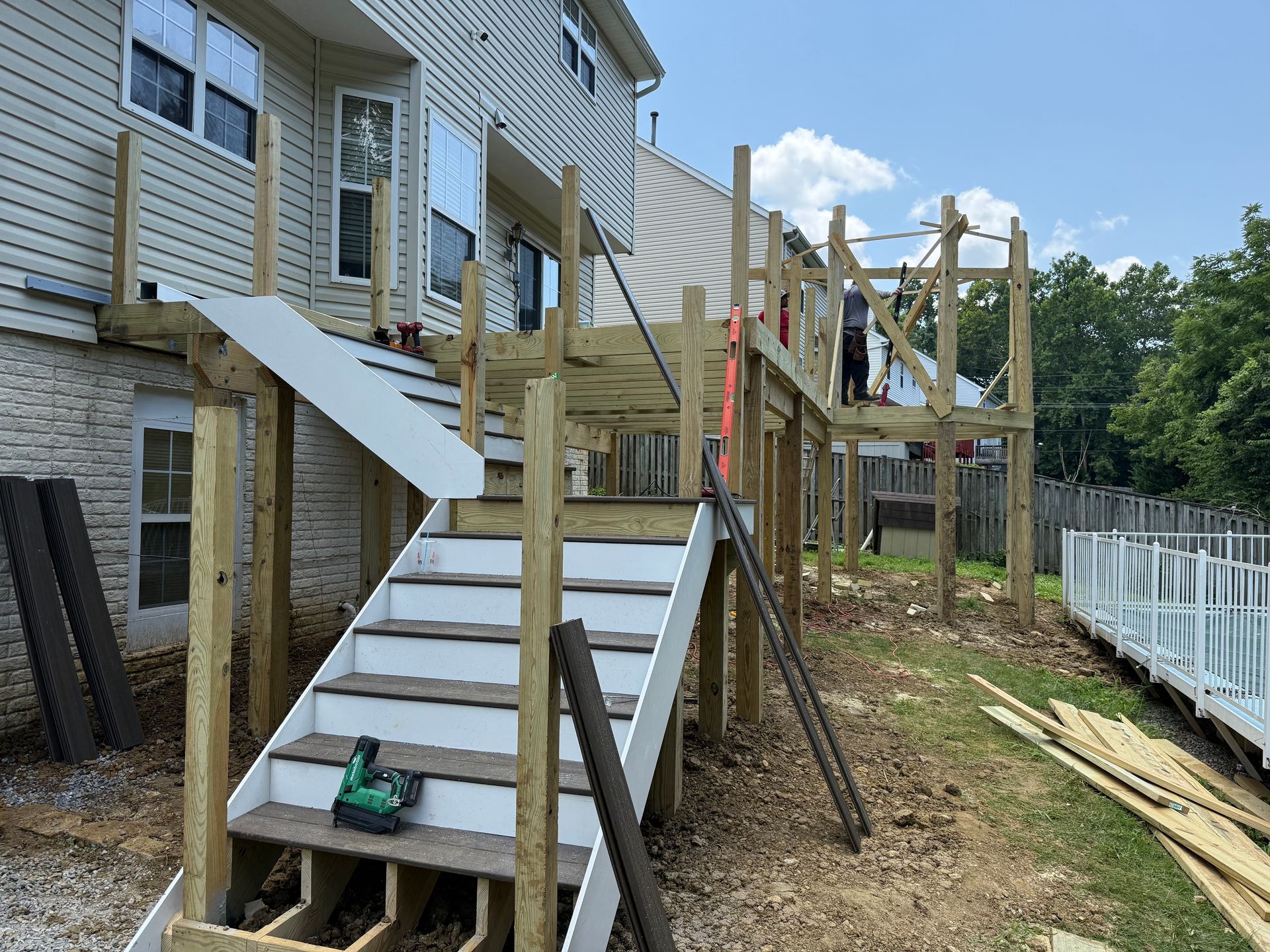 Backyard house renovation with wooden stairs and deck framing under construction
