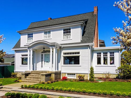 A large white house with a lush green lawn and a chimney.