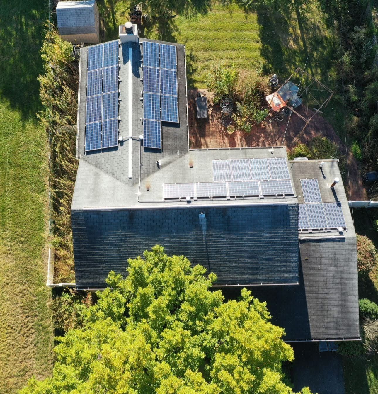 Aerial view of a house roof with solar panels and trees nearby