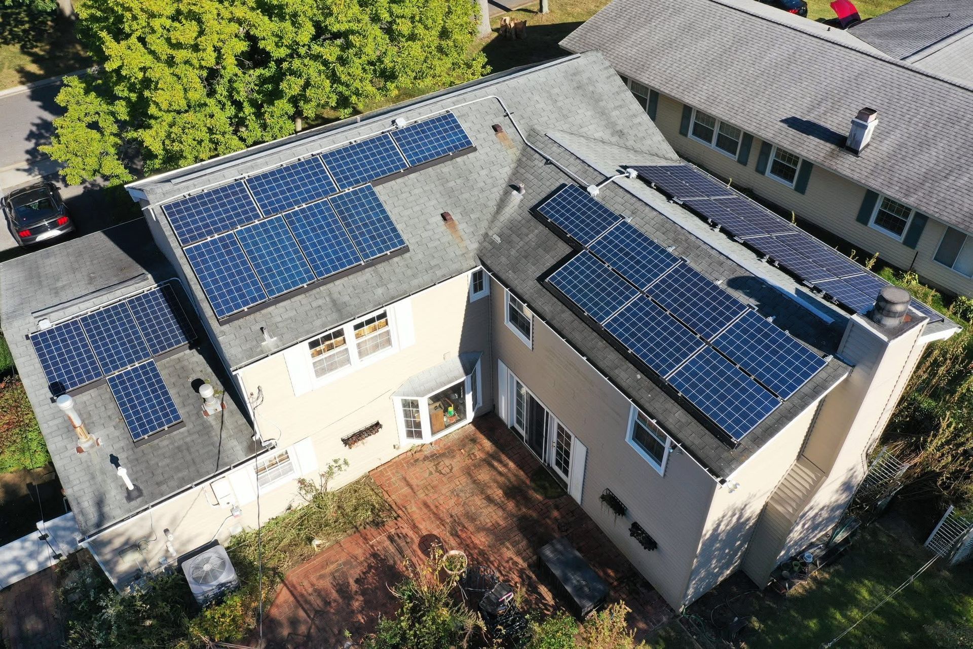 Aerial view of two white houses with blue solar panels on their roofs.