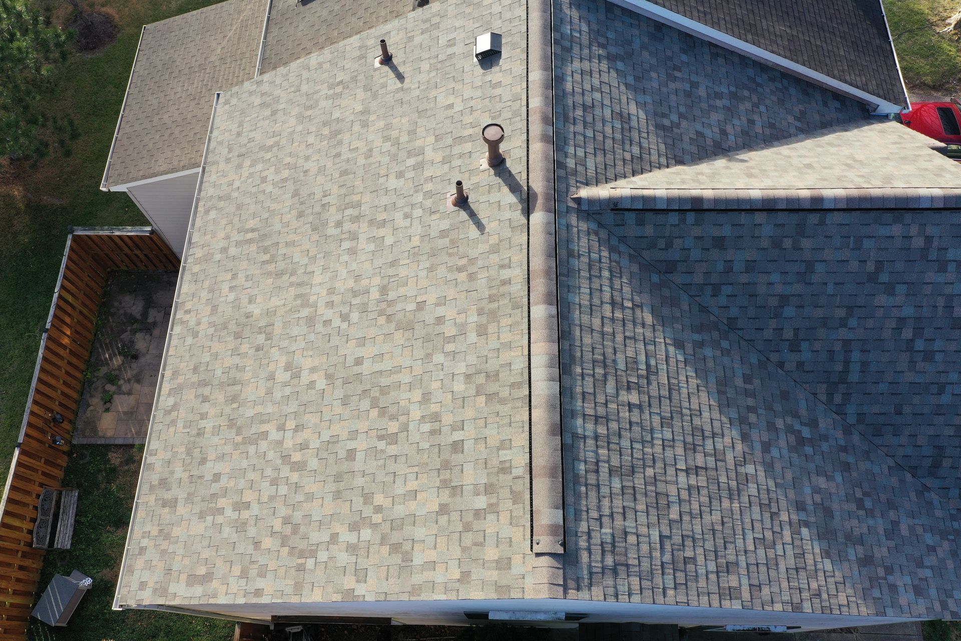 Aerial view of two adjacent house roofs with shingles, vents, and gutters.