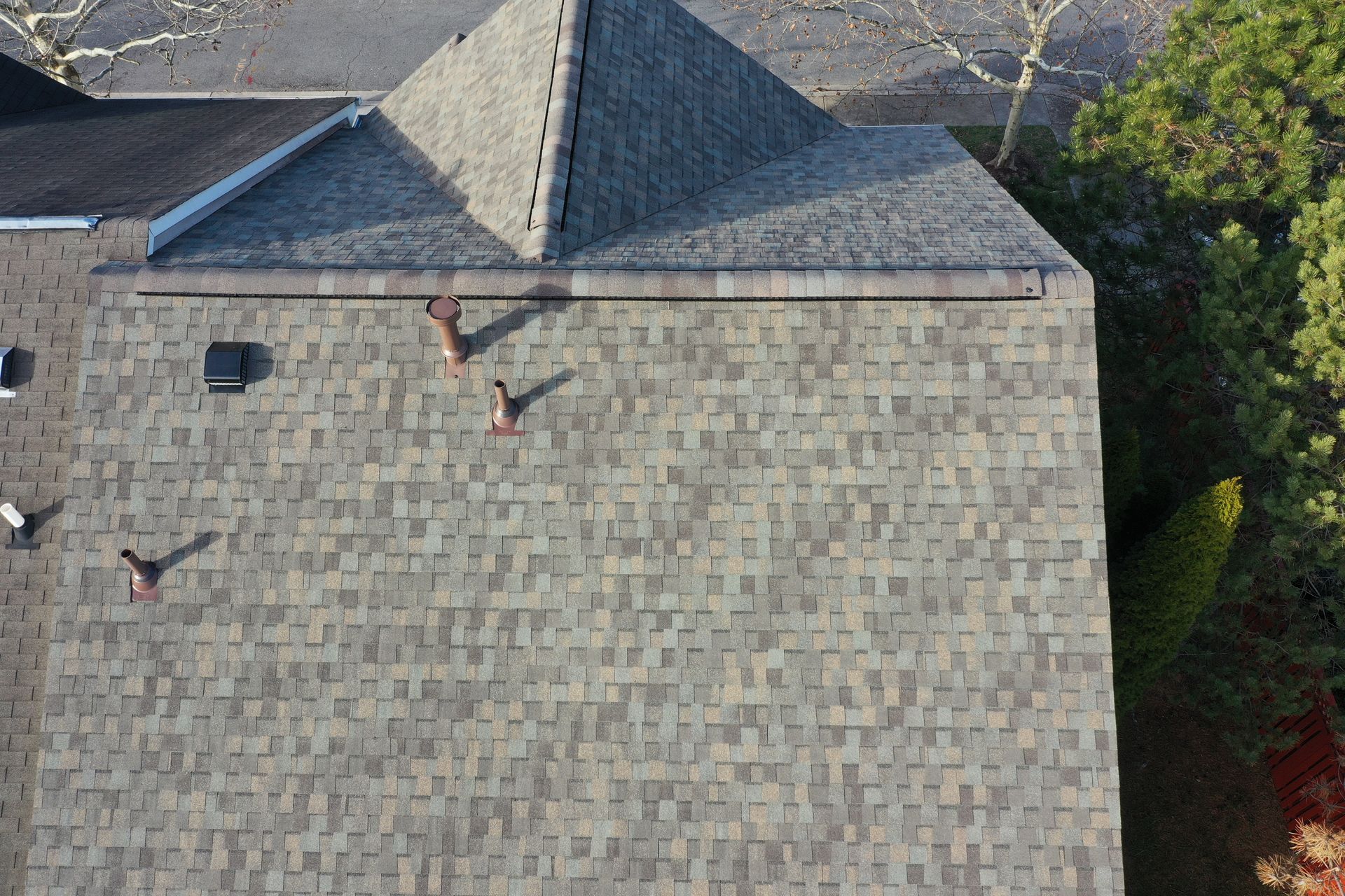 Aerial view of a gray shingled roof with three birds perched on it.