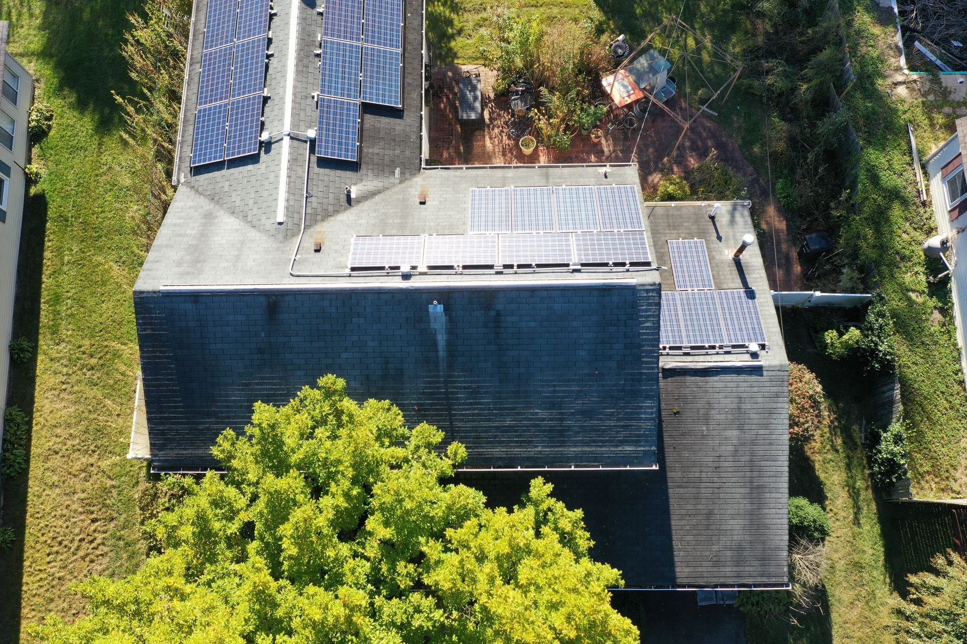 Aerial view of a house roof with solar panels and surrounding trees
