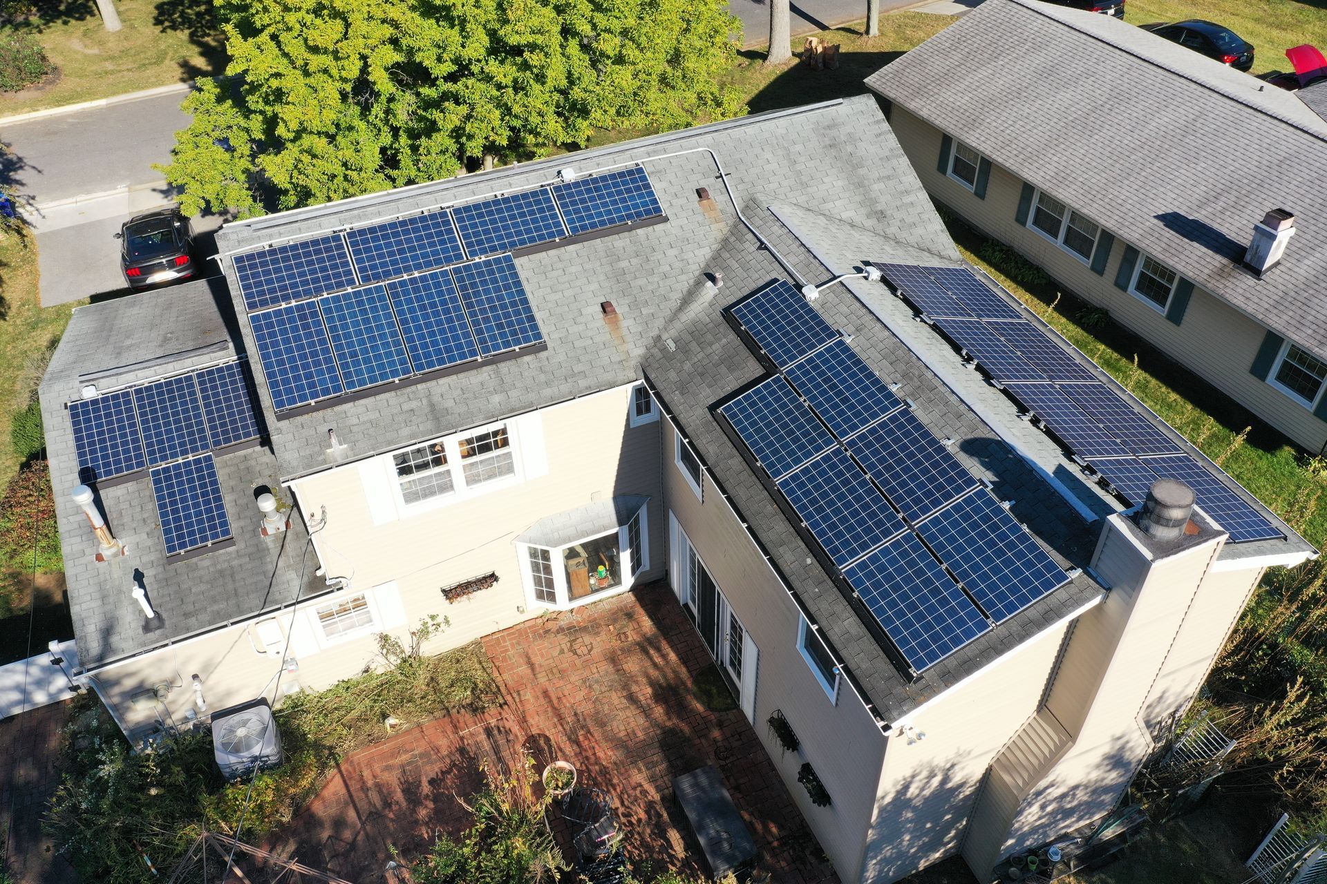 Aerial view of a house with multiple solar panel arrays on the roof.