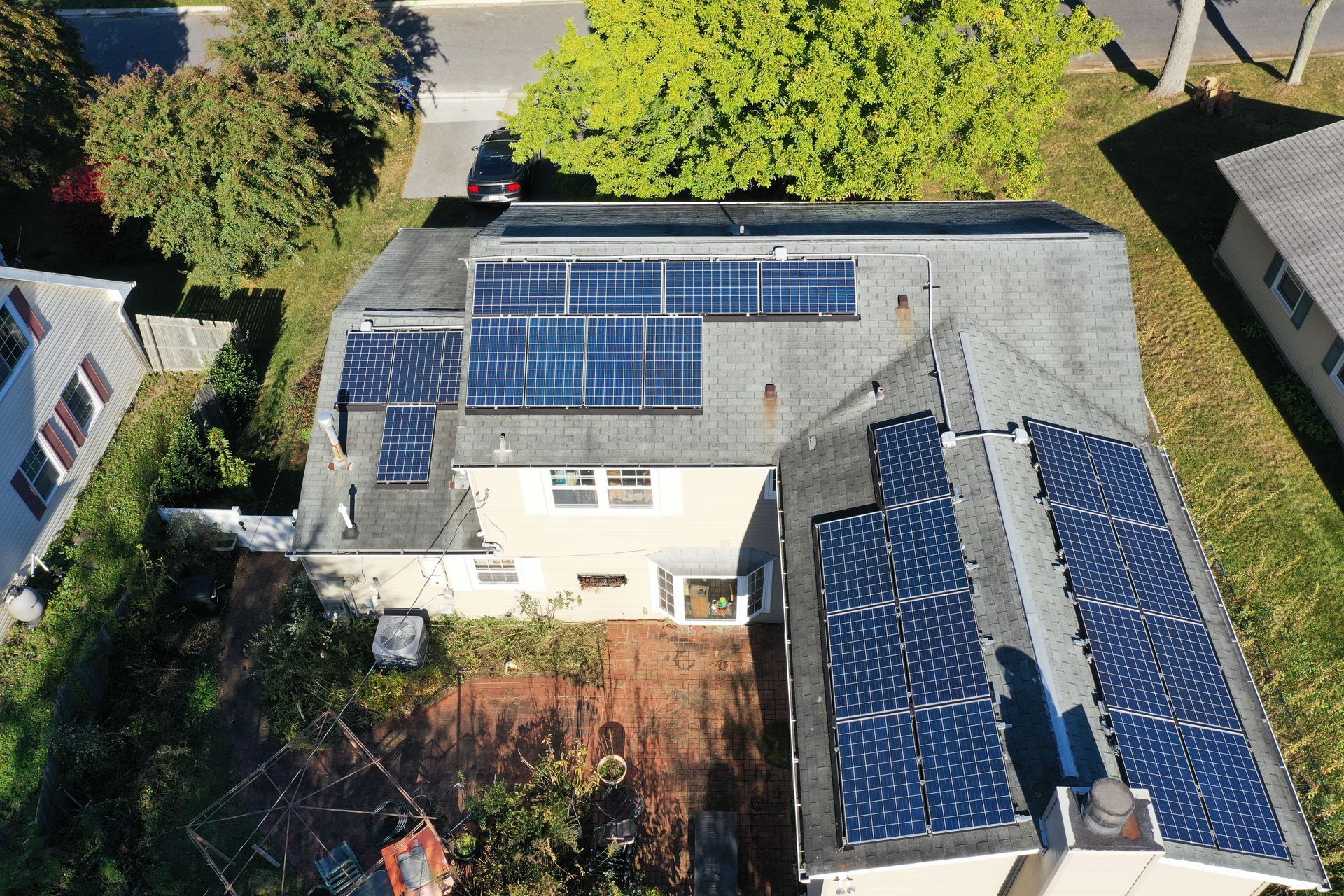 Aerial view of a house with rooftop solar panels and a backyard patio.