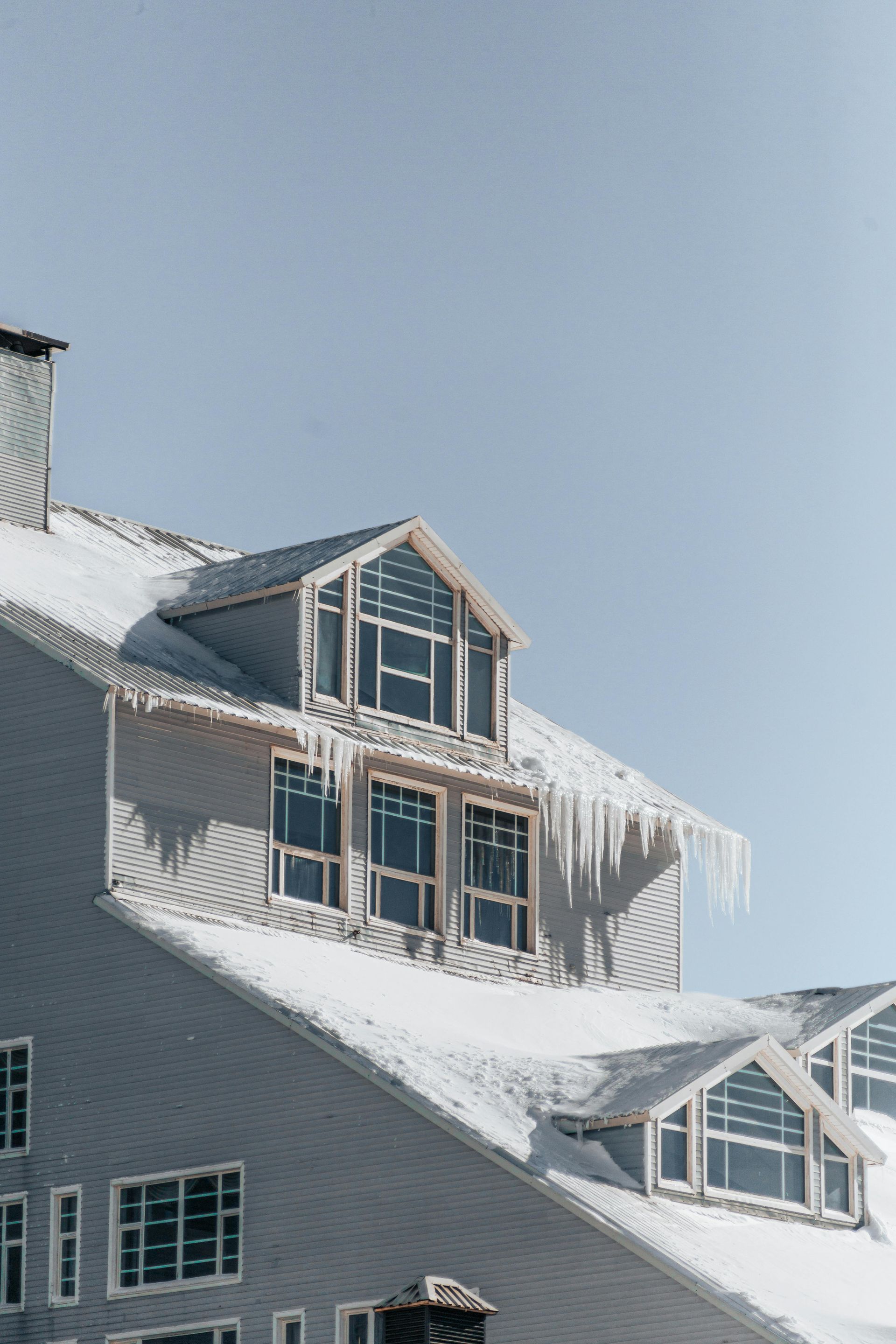 multi storey house with snow and ice on roof