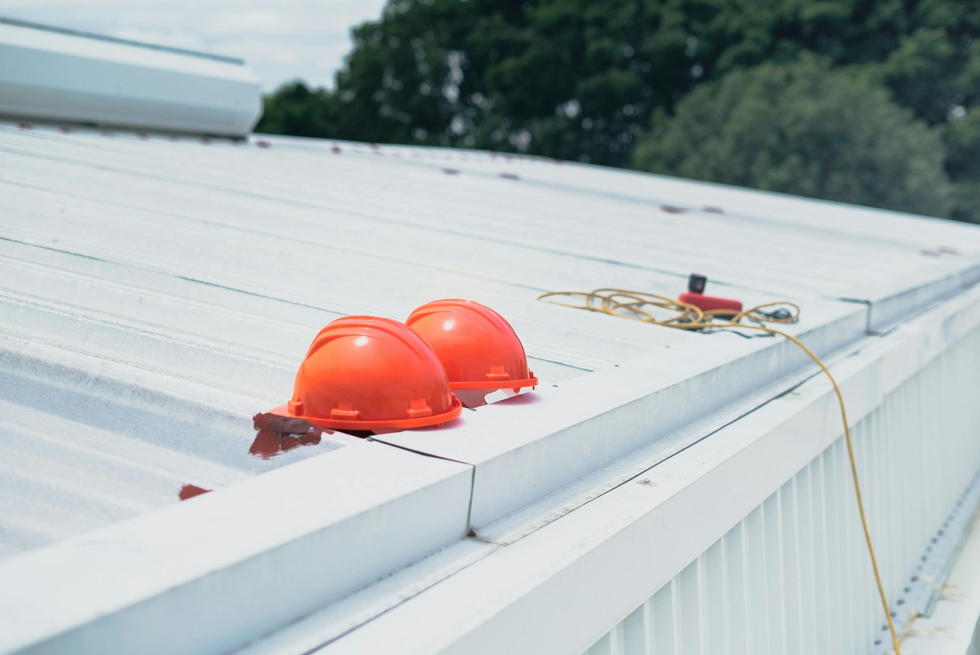 Two orange hard hats are sitting on top of a white commercial roof.
