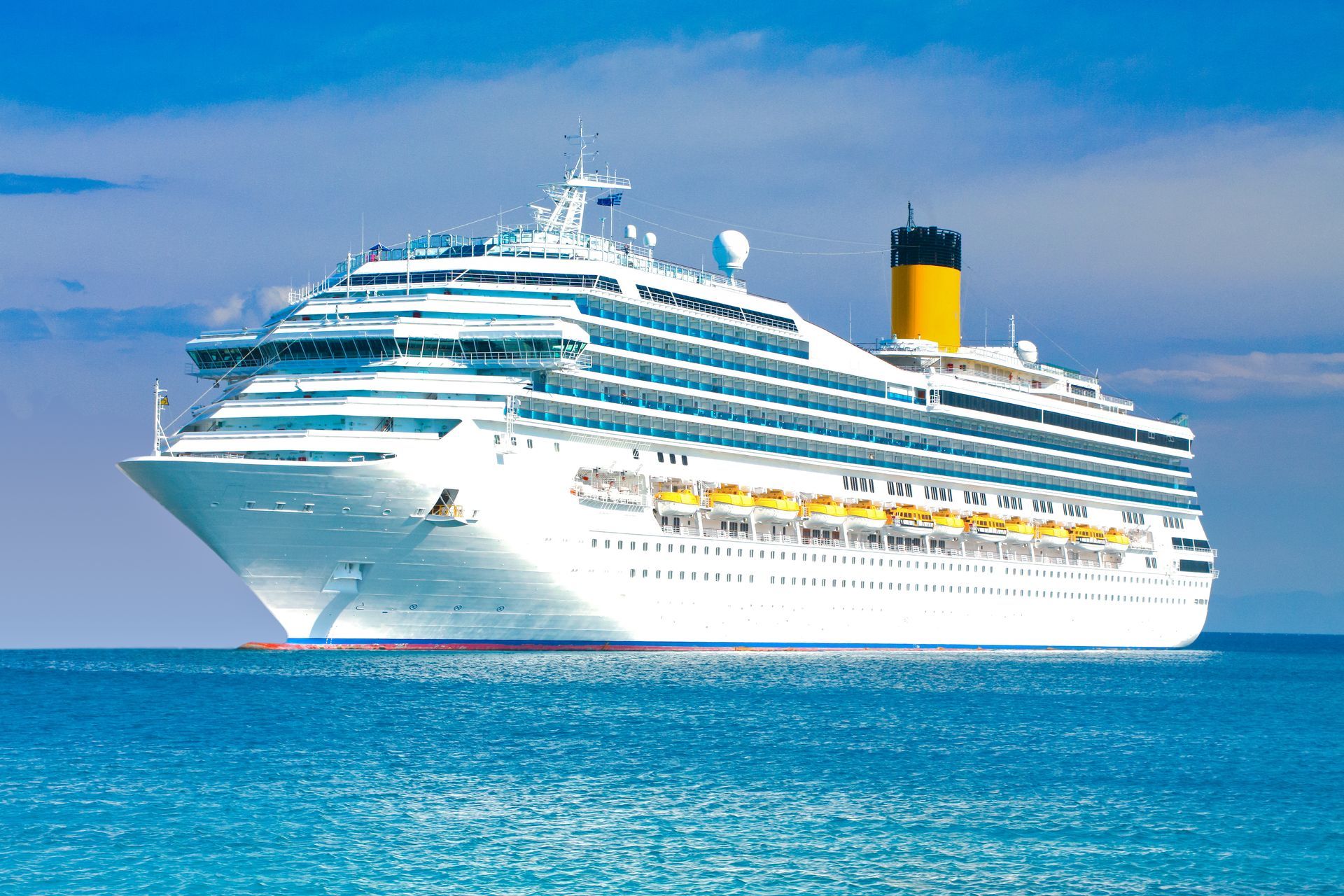 Large white cruise ship sailing on calm blue water under a clear sky