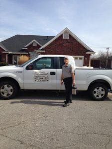 Person standing beside a white pickup truck in front of a brick house.