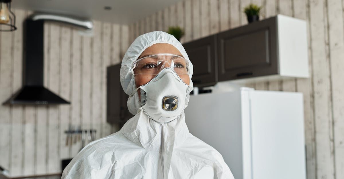 Person in white protective suit and mask standing in a kitchen