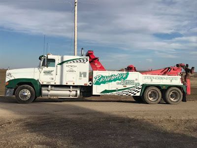 A white and green tow truck is parked on the side of the road.