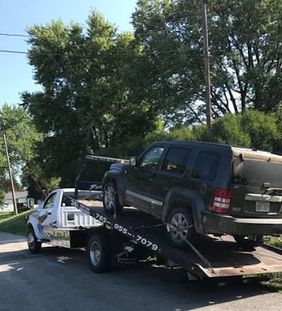 A black suv is being towed by a tow truck.