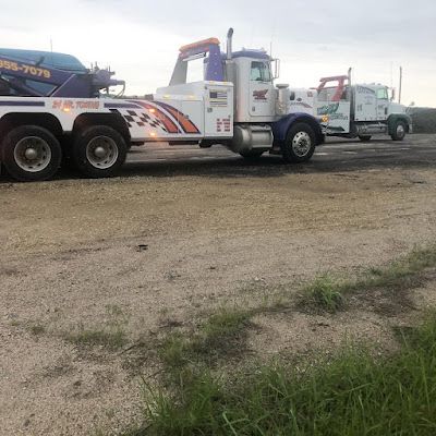 Two tow trucks are parked next to each other in a dirt lot.
