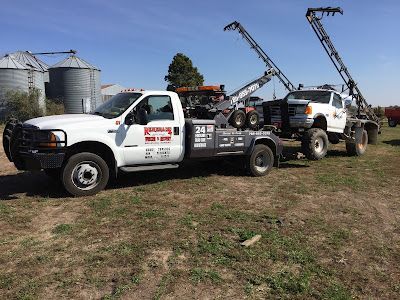 Two tow trucks are parked next to each other in a field.