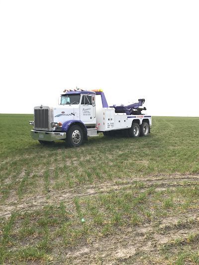 A white tow truck is parked in a grassy field.