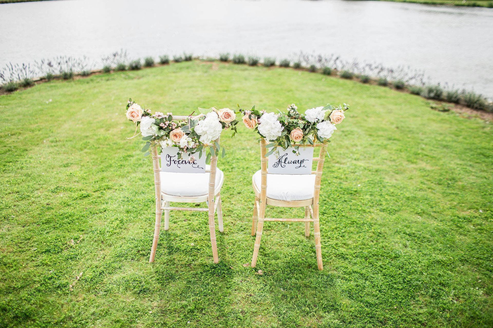 Two chairs decorated with flowers are sitting on top of a lush green field.