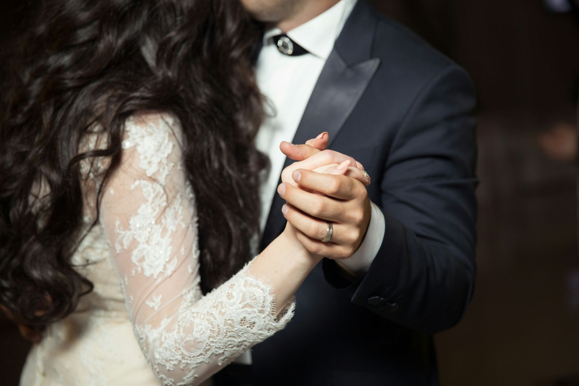 A bride and groom are holding hands while dancing at their wedding reception.
