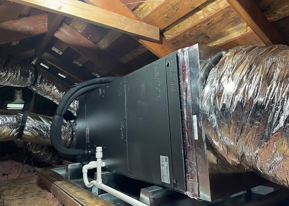 HVAC unit and ductwork installed in an attic with exposed wooden rafters