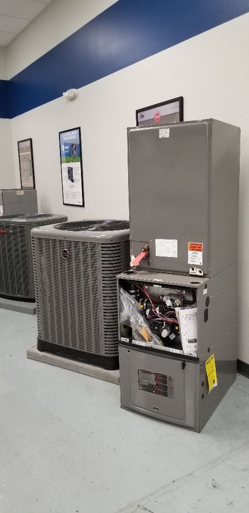Open HVAC unit in a utility room beside two closed gray units.