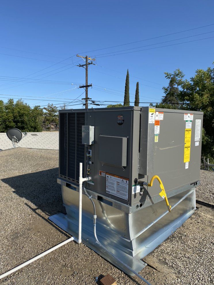 Outdoor HVAC unit on a metal pad beside a building, with utility poles and trees in the background