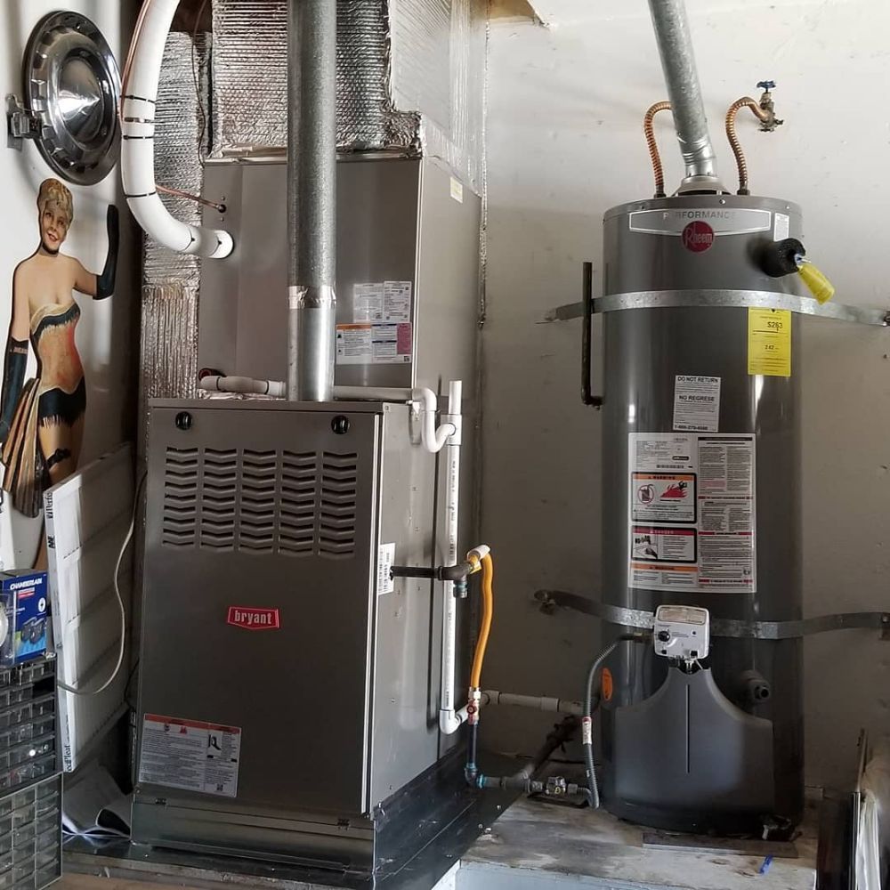 Furnace and water heater in a garage utility area with exposed ductwork and pipes