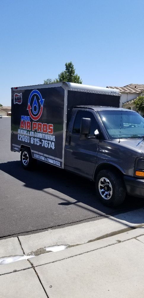 Black box truck with business signage parked on a sunny street corner