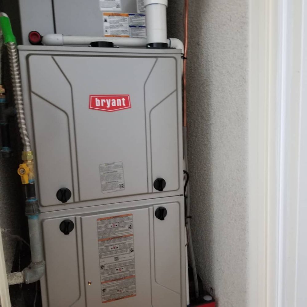 Gray Bryant furnace unit in a utility closet, with pipes and wall trim visible.
