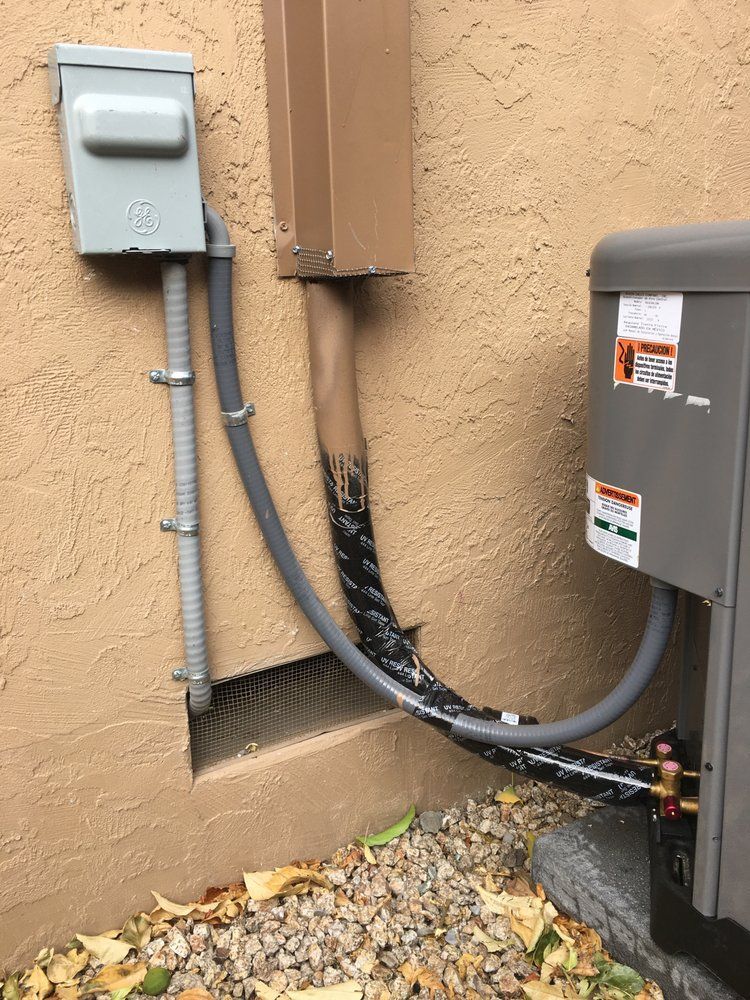 Outdoor electrical meters and conduit on a stucco wall beside an HVAC unit.