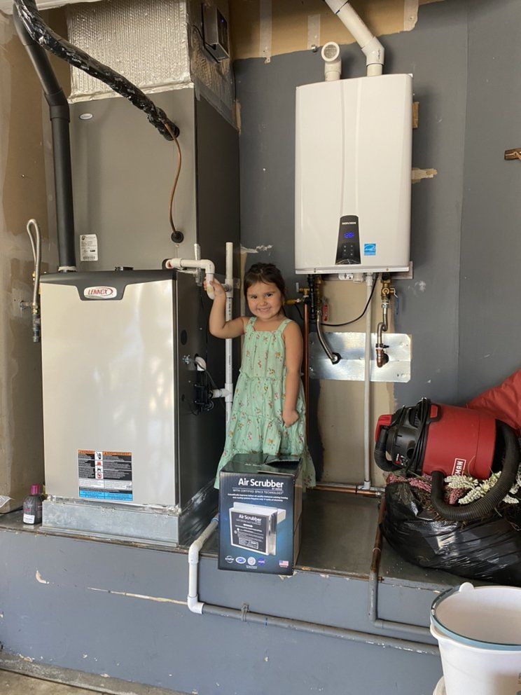 Young child standing in a utility room beside a furnace and water heater, holding a small step stool