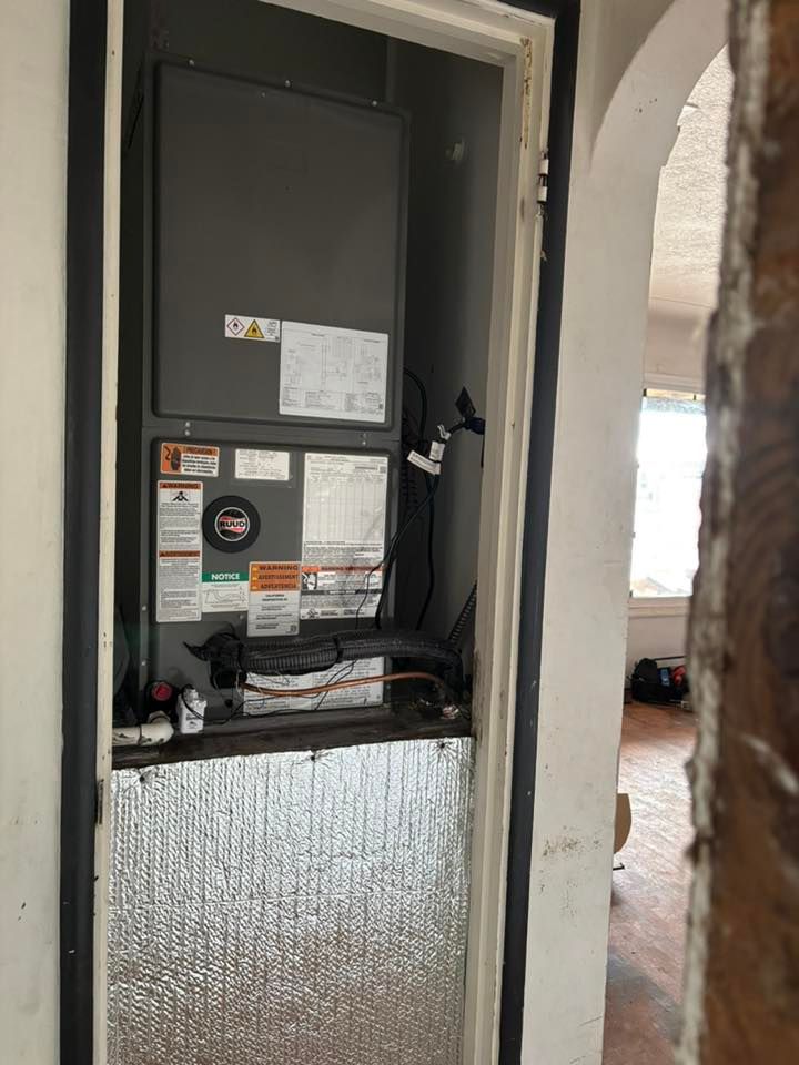 Open air handler cabinet in a doorway, with exposed wiring and control panels inside a home.