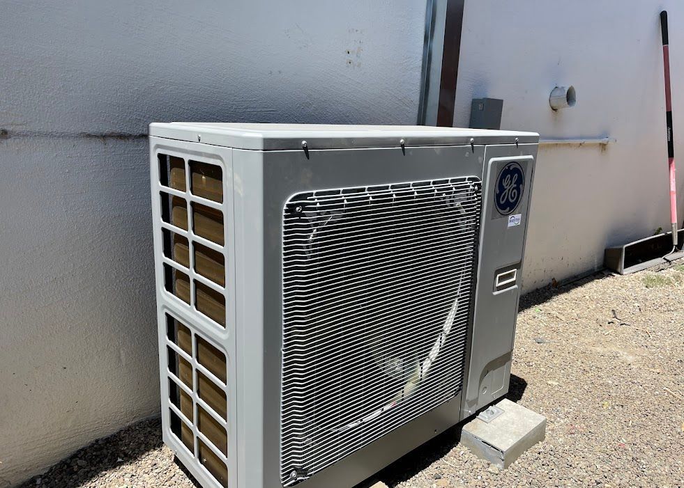 Outdoor HVAC heat pump unit beside a wall, with a large front fan and beige side vents.