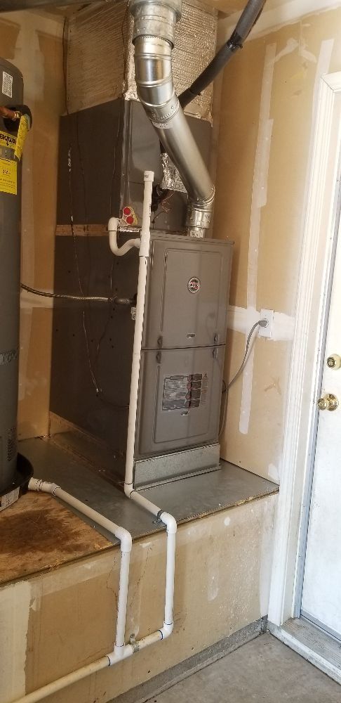 Furnace and ductwork in a narrow utility closet beside a doorway
