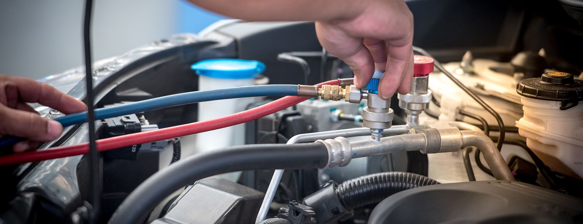 Hands adjusting engine hoses and fittings in a car engine bay