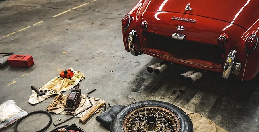A red car is being worked on in a garage.