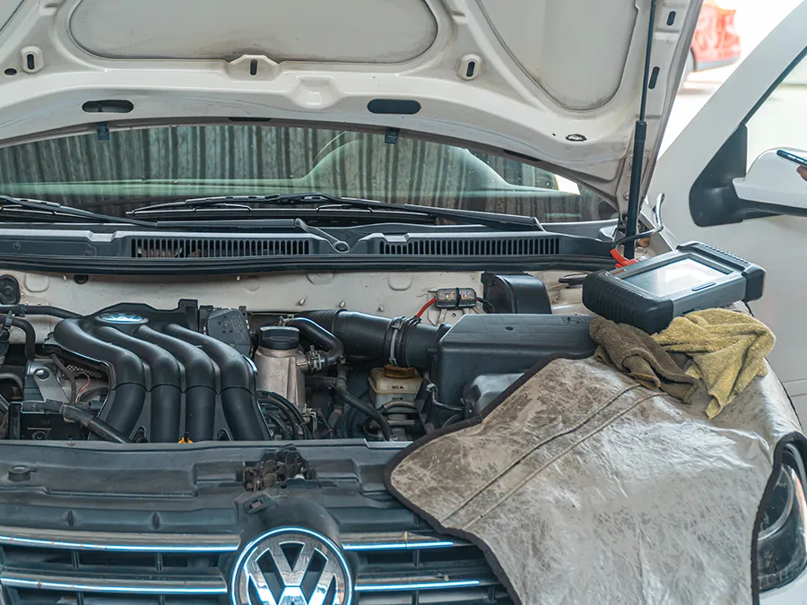 Volkswagen car engine bay open, with a cloth draped over the front grille.