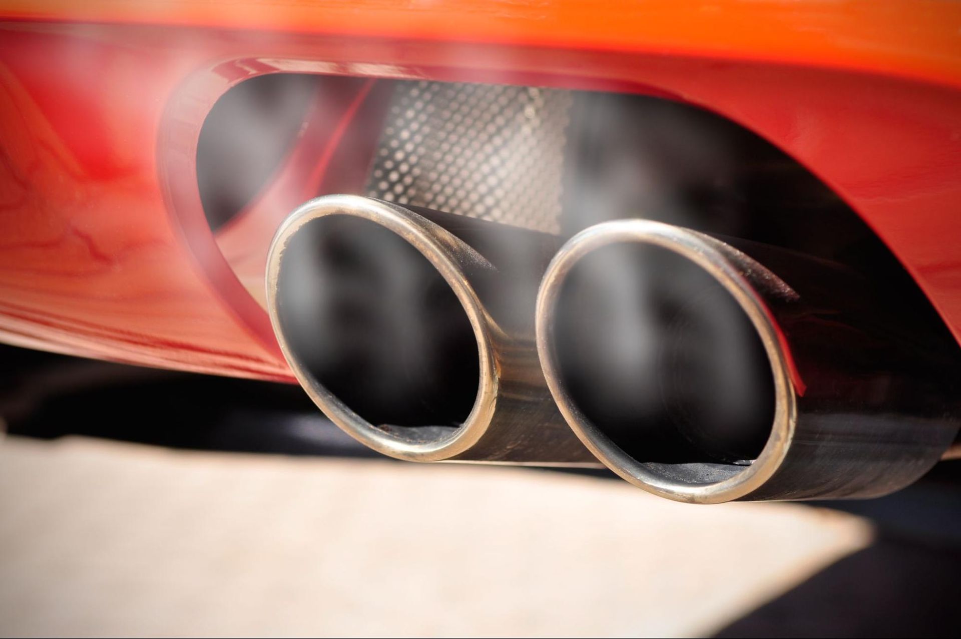 A close up of a car exhaust pipe with smoke coming out of it