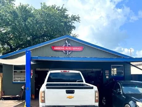 Exterior of Barrows Auto Service shop with a white pickup truck in front. The building has a red and white sign with an anchor logo.