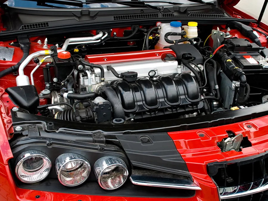 The engine of a red car is visible under the hood