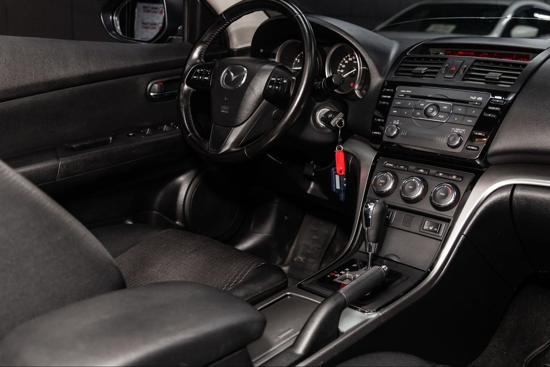 The interior of a black car with a steering wheel and dashboard.